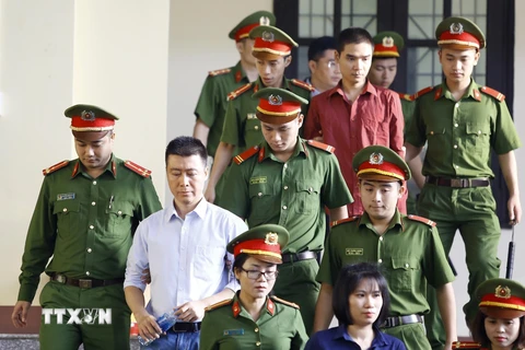 Bị cáo Phan Sào Nam (áo trắng) cùng các bị cáo được cơ quan chức năng dẫn giải ra tòa. (Ảnh: Trung Kiên/TTXVN)