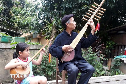 Nghệ nhân Dương Văn Thục truyền dạy cách đàn tính, hát then cho người cháu của mình. (Ảnh: Đức Hiếu/TTXVN)