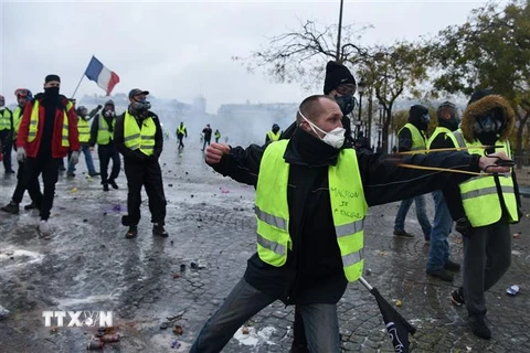 Người biểu tình "áo vàng" quá khích ném đá, bắn súng cao su vào cảnh sát tại Đại lộ Champs Elysees ở Paris. (Ảnh: AFP/TTXVN)