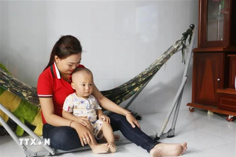 Cháu Nguyễn Quốc Huy đang được mẹ chăm sóc tại gia đình. (Ảnh: Phạm Minh Tuấn/TTXVN)