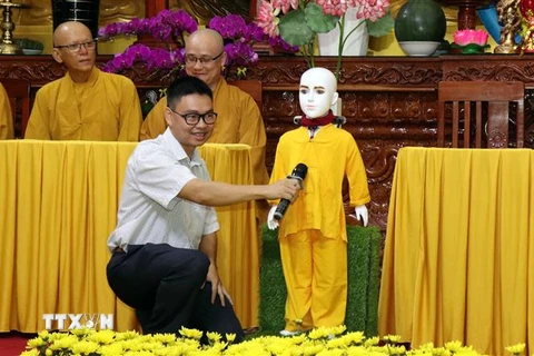Tiến sỹ, kỹ sư Nguyễn Bá Hải hướng dẫn người dân đặt câu hỏi về Phật pháp cho chú tiểu Giác Ngộ 4.0. (Ảnh: Xuân Khu/TTXVN)