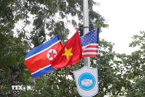 Cờ Mỹ, cờ Triều Tiên và cờ Việt Nam, bên dưới là biểu tượng hai bàn tay bắt chặt vào nhau thể hiện tinh thần của cuộc gặp lớn được treo trên các tuyến phố xung quanh hồ Hoàn Kiếm. (Ảnh: Danh Lam/TTXVN)