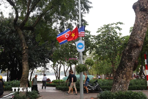 Cờ Mỹ, cờ Triều Tiên và cờ Việt Nam, bên dưới là biểu tượng hai bàn tay bắt chặt vào nhau thể hiện tinh thần của cuộc gặp lớn, được treo quanh hồ Hoàn Kiếm. (Ảnh: Danh Lam/TTXVN)