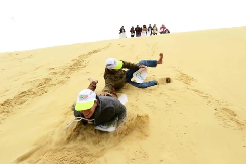 Du khách thích thú tham gia trò chơi trượt cát. (Ảnh: Mạnh Thành/TTXVN)