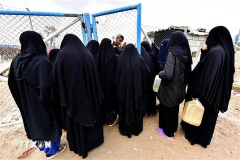 Phụ nữ tại trại tị nạn al-Hol, nơi sinh sống của thân nhân các thành viên tổ chức Nhà nước Hồi giáo (IS) tự xưng, xếp hàng chờ nhận lương thực ngày 28/3/2019. (Ảnh: AFP/ TTXVN)