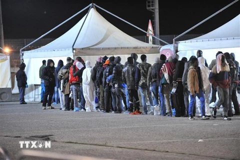 Người di cư trên tàu bảo vệ bờ biển Gregoretti xếp hàng chờ nhận lương thực cứu trợ tại cảng Corigliano, Italy, ngày 10/1/2015. (Ảnh: AFP/ TTXVN)