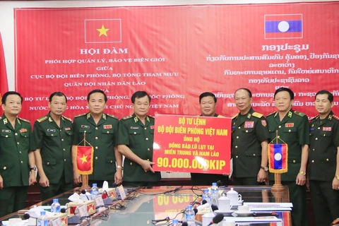 Trung tướng Hoàng Xuân Chiến (thứ 5, từ trái sang), Tư lệnh Bộ đội Biên phòng Việt Nam, trao tiền ủng hộ người dân bị thiệt hại tại các tỉnh Trung và Nam Lào cho Bộ Quốc phòng Lào. (Ảnh: Xuân Tú/TTXVN)