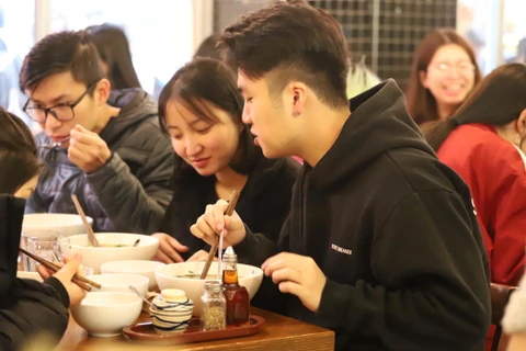 Các bạn trẻ du học sinh Việt Nam tại Melbourne thích thú thưởng thức Phở Thìn 13 Lò Đúc. (Ảnh: Diệu Linh/Vietnam+)