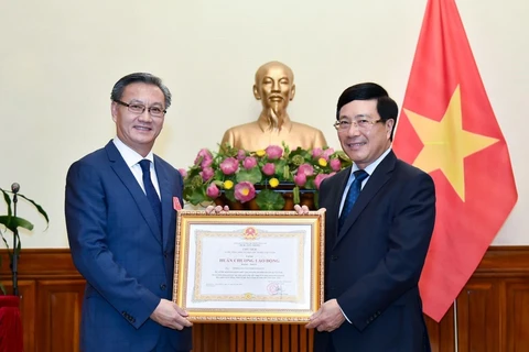 Bộ trưởng Bộ Ngoại giao Phạm Bình Minh trao Huân chương Lao động cho Đại sứ Lào tại Việt Nam Thongsavanh Phomvihane. (Ảnh: TTXVN)