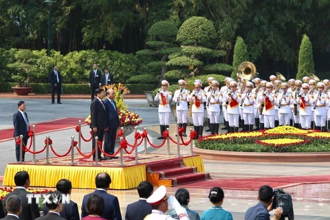 Thủ tướng Nguyễn Xuân Phúc và Thủ tướng Lào Thongloun Sisoulith nghe quân nhạc cử Quốc thiều hai nước. (Ảnh: Dương Giang/TTXVN)
