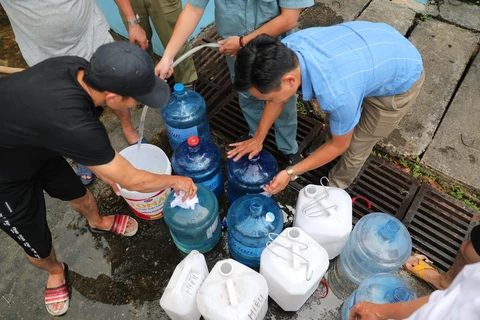 Người dân xếp hàng chờ lấy nước miễn phí tại Nhà máy nước Hạ Đình (địa chỉ, số 14 ngõ 192 phố Hạ Đình). (Ảnh: Thành Đạt/TTXVN)