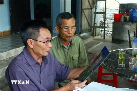 Ông Nguyễn Đình Sắt (bên trái và người thân đang vô cùng lo lắng trước thông tin con trai mình là Nguyễn Đình Tứ đi xuất khẩu lao động tại nước Anh và mất thông tin liên lạc. (Ảnh: Tá Chuyên/TTXVN)