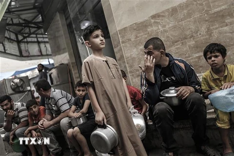 Người dân Palestine xếp hàng chờ nhận thực phẩm cứu trợ tại Dải Gaza. (Ảnh: AFP/TTXVN)