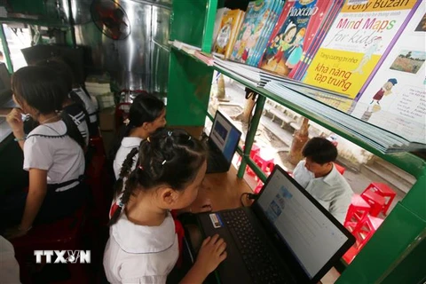 Các em học sinh trường Tiểu học Him Lam (thành phố Vị Thanh, tỉnh Hậu Giang) đọc sách, báo tại Xe thư viện lưu động đa phương tiện. (Ảnh: Duy Khương/TTXVN)