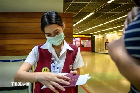 Nhân viên kiểm tra hộ chiếu của một hành khách tại sân bay Don Mueang ở Bangkok, Thái Lan ngày 21/1/2020. (Ảnh: AFP/TTXVN)