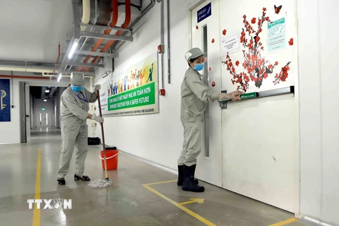 Lau sàn nhà và tay nắm cửa bằng dung dịch sát khuẩn tại Công ty trách nhiệm hữu hạn sản xuất hàng may mặc Việt Nam (TAL), khu công nghiệp Bá Thiện 2 (huyện Bình Xuyên). (Ảnh: Hoàng Hùng/TTXVN)