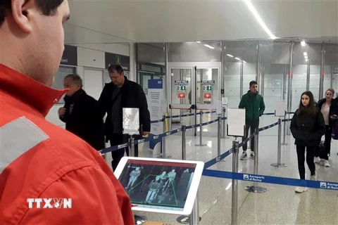 Nhân viên chữ thập đỏ dùng máy quét thân nhiệt để kiểm tra thân nhiệt hành khách tại sân bay Fiumicino, Rome, Italy, ngày 5/2/2020. (Ảnh: AFP/ TTXVN)