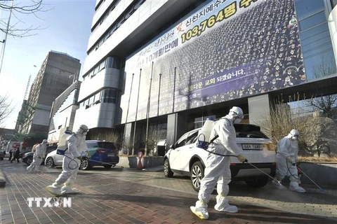 Nhân viên y tế phun thuốc khử trùng phía trước một nhà thờ của giáo phái Shincheonji ở Daegu, Hàn Quốc, nhằm ngăn chặn sự lây lan của COVID-19, ngày 19/2/2020. (Ảnh: AFP/ TTXVN)