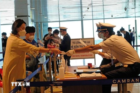 Lực lượng chức năng kiểm tra khai báo y tế của những hành khách đáp chuyến bay từ Hàn Quốc đến sân bay Cam Ranh chiều 25/2. (Ảnh: Nguyễn Dũng/TTXVN)