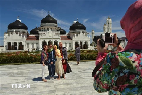 Khách du lịch nước ngoài thăm nhà thờ Hồi giáo Baiturrahman ở Banda Aceh, Indonesia. (Ảnh: AFP/TTXVN)