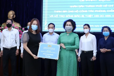Đại diện Tập đoàn Vạn Thịnh Phát (trái) trao tượng trưng số tiền ủng hộ cho Ủy ban Mặt trận Tổ quốc Việt Nam trong lễ phát động ủng hộ công tác phòng, chống dịch COVID-19 và ủng hộ đồng bào bị hạn hán, xâm nhập mặn. (Ảnh: TTXVN)