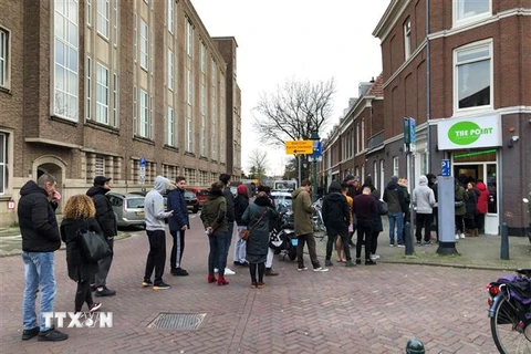 Người dân xếp hàng bên ngoài một quán cafe ở Hague, Hà Lan ngày 15/3/2020, trong bối cảnh dịch COVID-19 lan rộng. (Ảnh: AFP/ TTXVN)