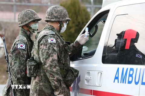 Binh sỹ Hàn Quốc kiểm tra thân nhiệt lái xe cứu thương đề phòng dịch COVID-19 tại căn cứ ở Bắc Daegu, cách Seoul khoảng 300km về phía Đông Nam ngày 26/2/2020. (Ảnh: YONHAP/TTXVN)