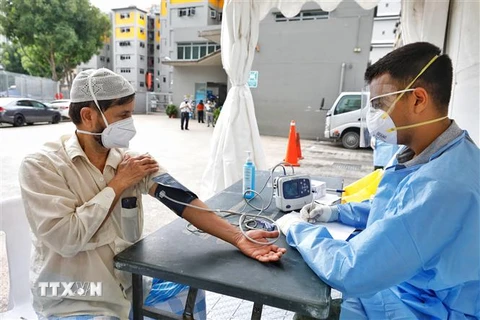 Nhân viên y tế kiểm tra sức khỏe cho người dân tại khu tập thể Toh Guan ở Singapore ngày 8/4/2020 trong bối cảnh dịch COVID-19 lan rộng. (Ảnh: THX/ TTXVN)