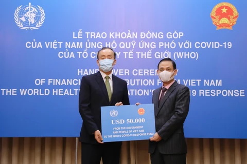 Thứ trưởng Bộ Ngoại giao Lê Hoài Trung trao tượng trưng số tiền 50.000 USD của Chính phủ và nhân dân Việt Nam đến Trưởng Đại diện Tổ chức Y tế Thế giới tại Việt Nam Kidong Park. (Ảnh: Lâm Khánh/TTXVN)