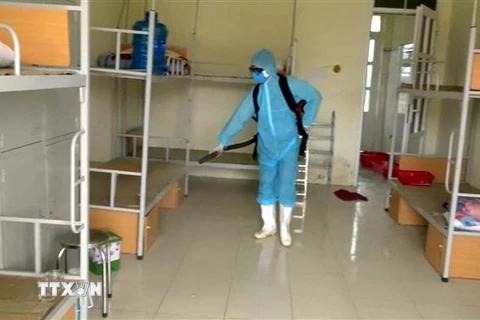 Nhân viên y tế phun thuốc khử khuẩn lại phòng của người bị cách ly. (Ảnh: Nguyễn Nam/TTXVN)