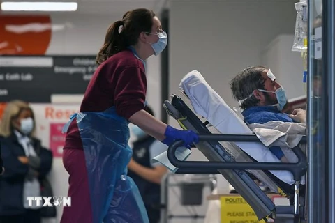 Nhân viên y tế chuyển bệnh nhân nhiễm COVID-19 tới bệnh viện ở London, Anh. (Ảnh: AFP/TTXVN)