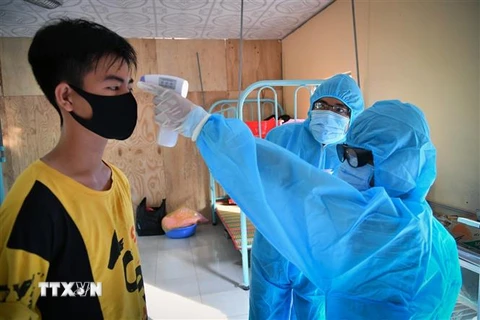 Cán bộ y tế tại khu cách ly ở thành phố Hà Tiên (Kiên Giang) đo thân nhiệt, kiểm tra sức khỏe công dân thực hiện cách ly. (Ảnh: Lê Huy Hải/TTXVN)