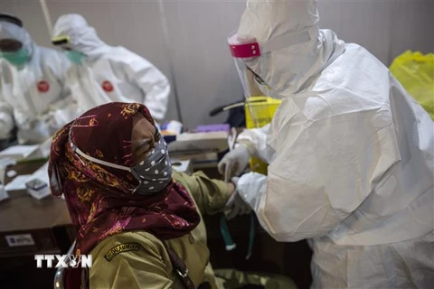 Nhân viên y tế lấy mẫu xét nghiệm COVID-19 tại Surabaya, Indonesia. (Ảnh: AFP/TTXVN)