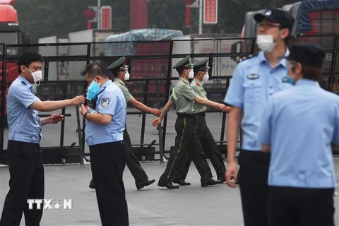 Cảnh sát gác tại lối vào chợ Tân Phát Địa ở Bắc Kinh, Trung Quốc, ngày 13/6, sau khi chợ phải đóng cửa do phát hiện ca nhiễm COVID-19 mới. (Ảnh: AFP/TTXVN)