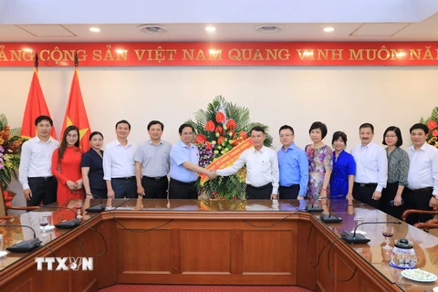Thứ trưởng Bộ Văn hóa, Thể thao và Du lịch Tạ Quang Đông (bên trái) chúc mừng Thông tấn xã Việt Nam. (Ảnh: Dương Giang/TTXVN)