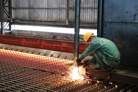 Công nhân Nhà máy cán thép Thái Trung (Công ty Cổ phần gang thép Thái Nguyên) lấy mẫu thép mới cán. (Ảnh: Hoàng Nguyên/TTXVN)