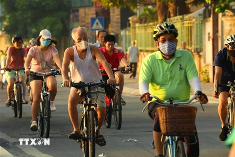Người dân đeo khẩu trang tập thể dục sáng sớm trên phố Trích Sài, Tây Hồ. (Ảnh: Lâm Khánh/TTXVN)