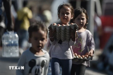 Trẻ em nhận thức ăn và nước uống cứu trợ sau vụ cháy trại tị nạn Moria trên đảo Lesbos, Hy Lạp, ngày 10/9/2020. (Ảnh: AFP/TTXVN)