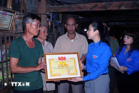 Đại diện gia đình anh Quàng Văn Xôm nhận Bằng khen từ Bí thư Tỉnh đoàn Sơn La Cầm Thị Huyền Trang. (Ảnh: Quang Quyết/TTXVN)
