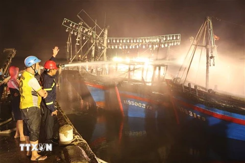 Lực lượng chữa cháy nỗ lực dập lửa trên tàu cá. (Ảnh: Nguyễn Oanh/TTXVN)