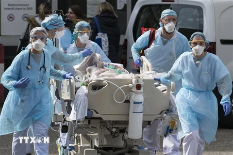 Nhân viên y tế chuyển bệnh nhân COVID-19 tại bệnh viện ở Mulhouse, Pháp, ngày 22/3/2020. (Ảnh: AFP/ TTXVN)