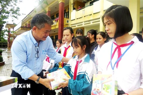 Các nhà hảo tâm trao tặng tập vở cho học sinh vùng lũ xã An Ninh, huyện Quảng Ninh. (Ảnh: Võ Dung/TTXVN)