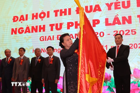 Chủ tịch Quốc hội Nguyễn Thị Kim Ngân gắn Huân chương Lao động hạng Nhất lên lá cờ truyền thống của ngành Tư pháp. (Ảnh: Doãn Tấn/TTXVN)