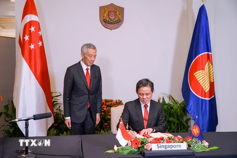 Bộ trưởng Chan Chun Sing ký RCEP dưới sự chứng kiến của Thủ tướng Lý Hiển Long. (Ảnh: MCI/TTXVN)