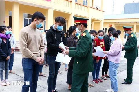 Cán bộ Bộ Chỉ huy Quân sự và Sở Y tế tỉnh Hòa Bình trao giấy chứng nhận hoàn thành thời gian cách ly y tế tập trung cho sinh viên Lào. (Ảnh: Thanh Hải/TTXVN)