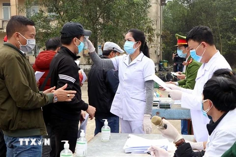 Kiểm tra y tế trước khi người dân hoàn thành cách ly về quê đón Tết. (Ảnh: Công Tường/TTXVN)
