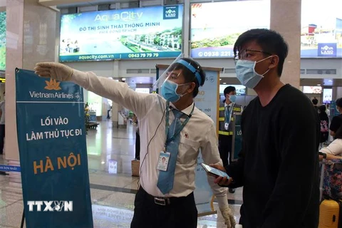 Các nhân viên hướng dẫn hành khách đến khu vực làm thủ tục lên máy bay tại sân bay Tân Sơn Nhất. (Ảnh: Tiến Lực/TTXVN)