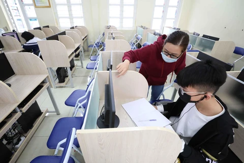 Học sinh trường THCS Thăng Long (Ba Đình, Hà Nội) không có điều kiện học trực tuyến tại nhà được nhà trường bố trí và phân công giáo viên giúp đỡ học tại phòng máy của trường. (Ảnh: Thanh Tùng/TTXVN)