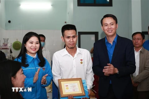 Đại diện Trung ương Đoàn trao Huy hiệu Tuổi trẻ dũng cảm tặng anh Nguyễn Ngọc Mạnh. (Ảnh: TTXVN phát)
