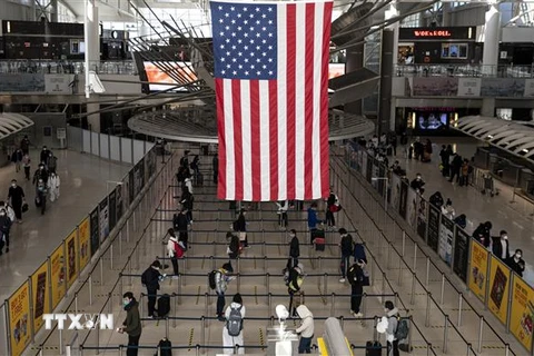 Hành khách chờ làm thủ tục tại sân bay John F. Kennedy ở New York, Mỹ ngày 13/5/2020. (Ảnh: AFP/TTXVN)